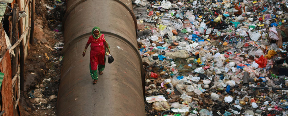 Woman walks along a water pipe in Dharavi