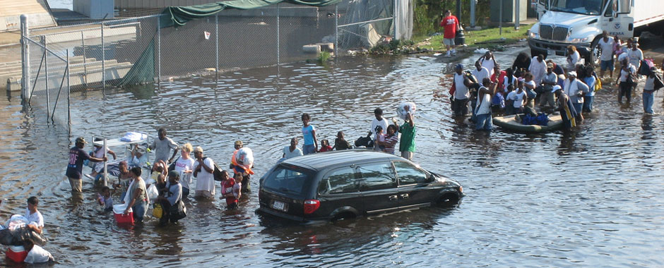 A crowd of people walk through deep flooding in New Orleans