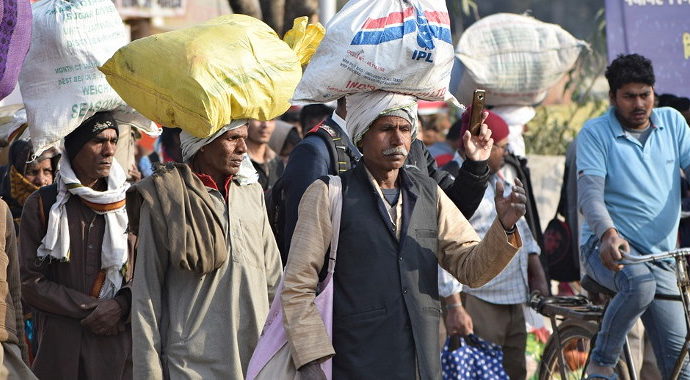 Men walking in the street carrying large bags of food