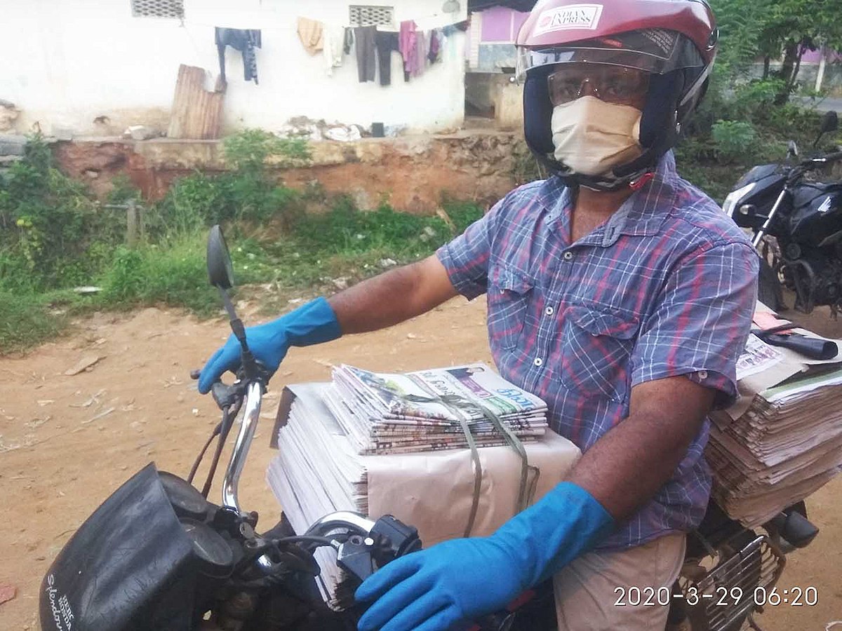 Newspaper vendor on motorcycle with protective equipment