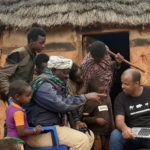 Group of people in Borana looking at photos on a laptop